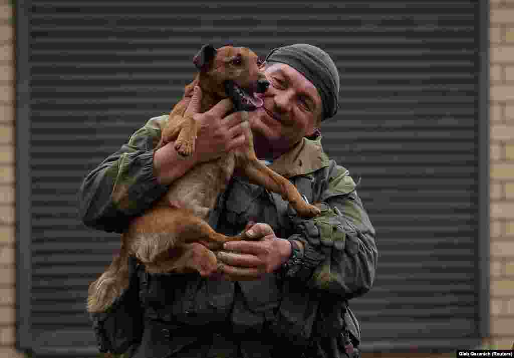 Un militar ucrainean este fotografiat în timp ce mângâie un câine în orașul Zolochiv, în regiunea Harkov proaspăt eliberată, Ucraina, 12 septembrie 2022.