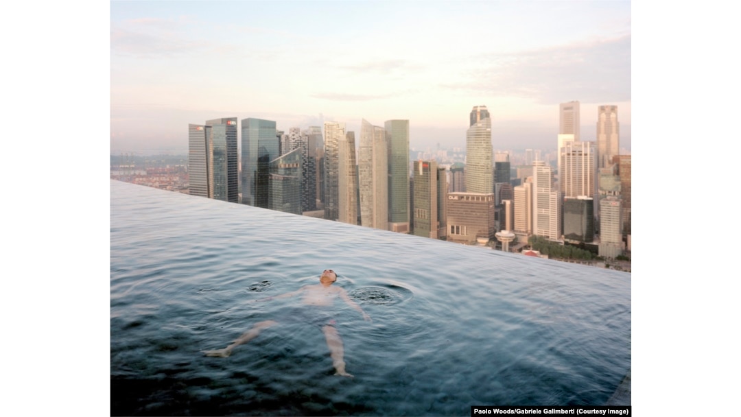 A man floats in the 57th-floor swimming pool of the Marina Bay Sands Hotel, with the skyline of “Central,” Singapore's financial district, in the background.