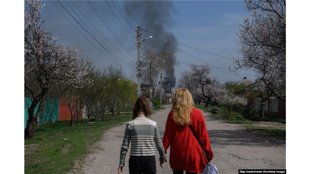 Žene idu predgrađem Harkiva dok gori vatra u blizini 9. aprila.