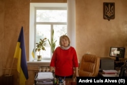 A shiny piece of shrapnel is stuck in the ceiling above Olena Sharkova's desk in the Myropillya village council.
