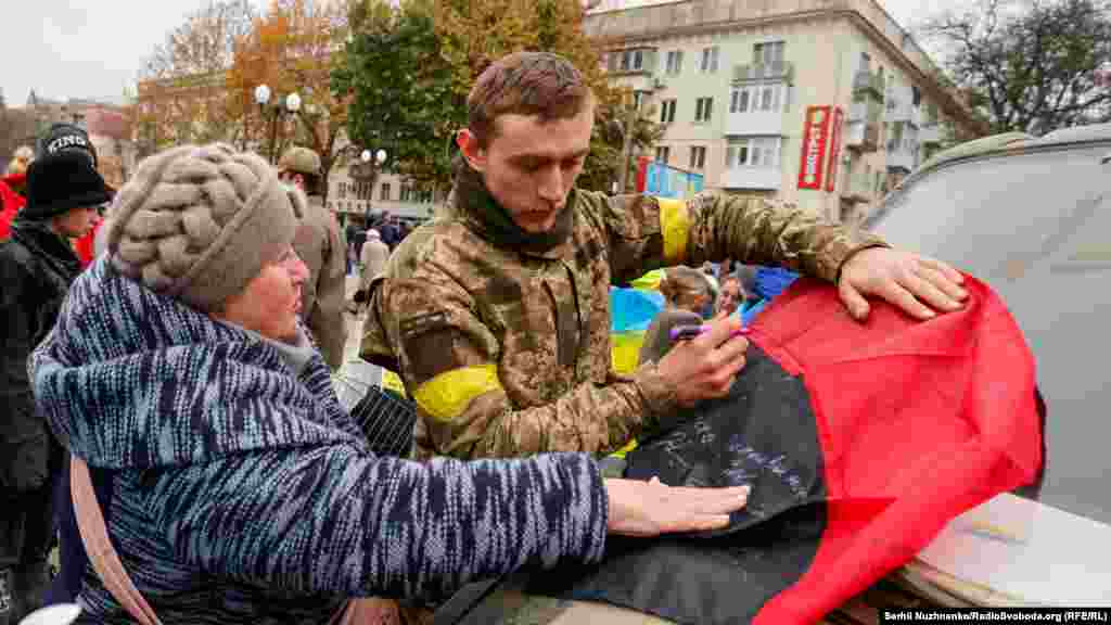 Військові підписують на пам'ять про звільнення Херсону також червоно-чорні прапори 