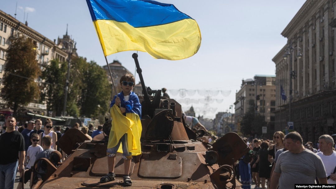 A boy waves a Ukrainian flag on top of an armored personal carrier at an exhibition of destroyed Russian military vehicles and weapons in the center of Kyiv dedicated to the country's upcoming Independence Day on August 24. 