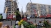 Люди несуть квіти, свічки та іграшки до будинку, зруйнованого російською ракетою, Дніпро, 16 січня 2023 року