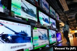 Ресей Украинаға басып кіргені туралы жаңалықты теледидардан көріп тұрған Гонконг тұрғыны. 24 ақпан 2022 жыл.