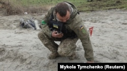 Украинский военный сапёр подбирает неразорвавшиеся части кассетной бомбы