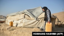 یوه افغانه مېرمن خپلې کېږدۍ ته اوبه وړي: انځور له ارشیفه