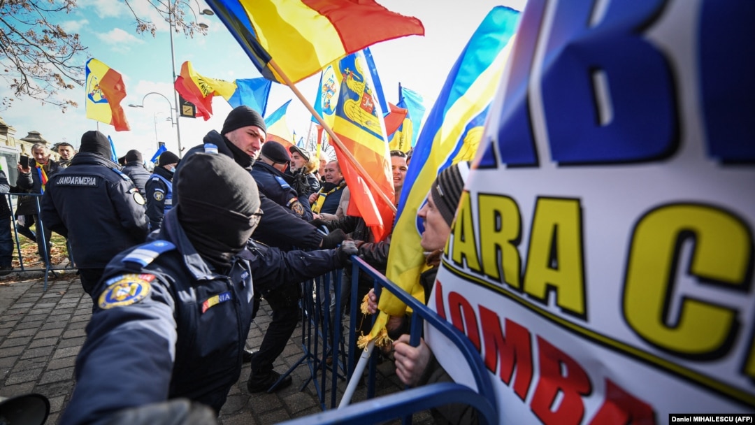 Romanian police push back protesters trying to enter the secured perimeter of the Romanian parliament headquarters during a demonstration in Bucharest on December 21.