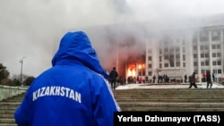 Өрттөнүп жаткан мэриянын алдында жүргөн адамдар. Алматы. 5 январь, 2022-жыл.