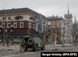 Російські війська розвантажують бронетехніку неподалік шпилеподібної вежі у квітні 2022 року