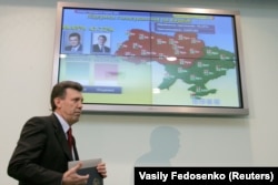 Глава Центральной избирательной комиссии Украины Сергей Кивалов проходит мимо экрана с предварительными результатами второго тура президентских выборов утром 22 ноября 2004 года