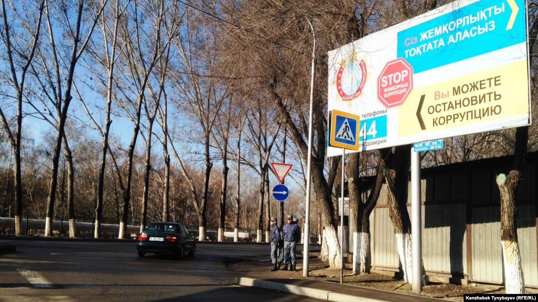 Полицейские рядом с билбордом, призывающим к борьбе с коррупцией. Алматы, 21 марта 2015 года.