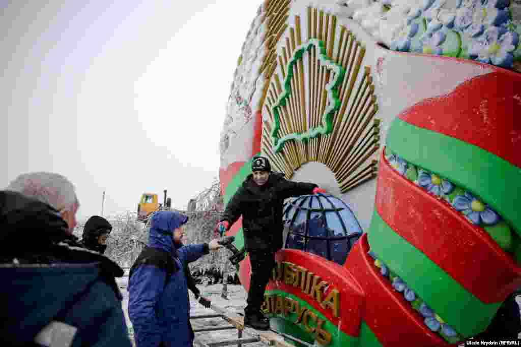Рабочыя мацуюць дзяржаўны герб побач з Нацыянальным аэрапортам, 29 студзеня 