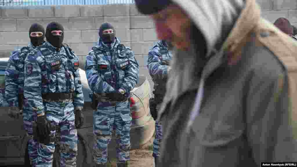 Мусульманин проходить повз російських силовиків, які заблокували збори кримськотатарської правозахисної організації «Кримська солідарність», що обстоює права майже двох сотень кримчан, переважно кримських татар і мусульман, яких правозахисники вважають політв'язнями. Судак, 28 січня 2018 року, фото Антона Наумлюка