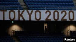 Član osoblja nosi zaštitnu masku na praznom međunarodnom stadionu u Jokohami tokom fudbalskog meča između Obale Slonovače i Saudijske Arabije, Japan, 22. juli 2021. 