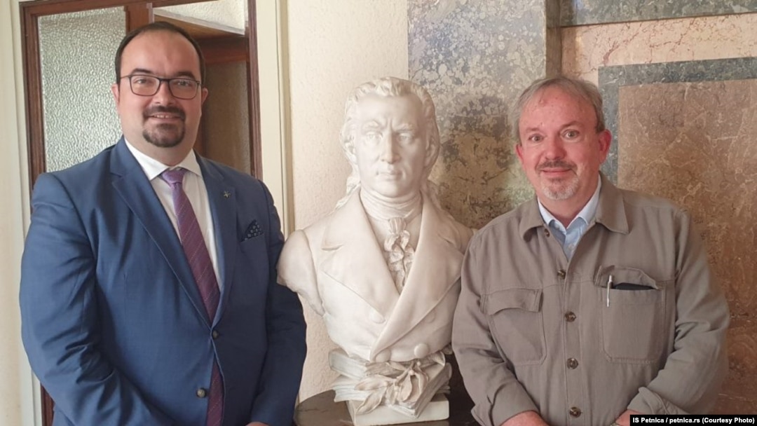Nikola Božić (levo) u istraživačkoj stanici Petnica sa bivšim direktorom Vigorom Majićem (desno), pored biste prvom ministru prosvete Srbije Dositeju Obradoviću. Datum nastanka fotografije na sajtu ove institucije nije naznačen. 