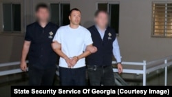 A photo provided by Georgia's State Security Service appears to show officers escorting Giorgi Bachiashvili in handcuffs. 