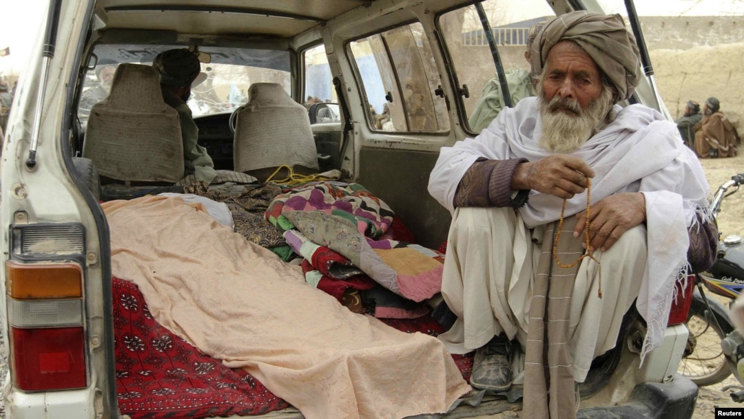 An elderly man sits next to the covered bodies of Afghans killed after what is believed to have been a shooting rampage by a U.S. soldier in Kandahar Province on March 11.