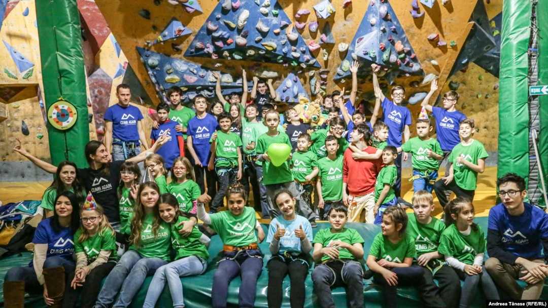 Copii cu diverse dizabilități și instructori Climb Again pozează la finalul petrecerii de Crăciun, organizată la sala de escaladă Galactic Gym din București.