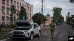 Украинский военный идет мимо поврежденного обстрелами здания в Судже в Курской области России