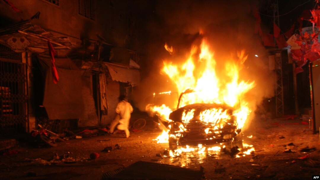 A Pakistani man runs past a burning vehicle after a suicide-bomb attack on an election campaign rally in Peshawar on April 16.