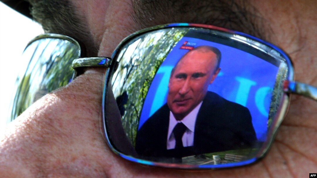 Видеокадр с президентом России Владимиром Путиным отражается на линзе очков телезрителя. Севастополь, 17 апреля 2014 года. 