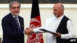 Afghan presidential candidates Abdullah Abdullah (left) and Ashraf Ghani shake hands after signing a power-sharing agreement at the Presidential Palace in Kabul on September 21.