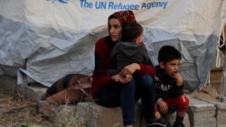 Suriye qadını ve balaları Iraq şimalinde qaçaqlar lagerinde çadır ve diger yardım almağa istey, 2019 senesi oktâbrniñ 17-si. Nümüneviy resim