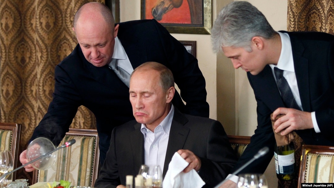 Євгеній Пригожин (ліворуч) допомагає Володимиру Путіну під час вечері з іноземними науковцями та журналістами в ресторані Cheval Blanc. 11 листопада 2011 року