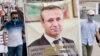 Участники митинга в поддержку Орхана Инанды несут плакат с его изображением. 