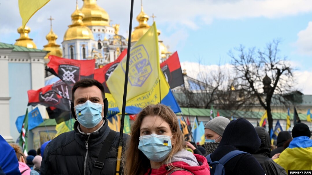 Молоді люди у захисних масках на акції у День українського добровольця біля Михайлівського собору в Києві, що належить ПЦУ, 14 березня 2020 року