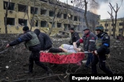 Орус аскерлери Мариуполдогу төрөт үйүнө жана балдар ооруканасына абадан сокку урганда жабыр тарткан кош бойлуу аялды украин куткаруучулар жана ыктыярчылар көтөрүп баратышат. 2022-жыл, 9-март