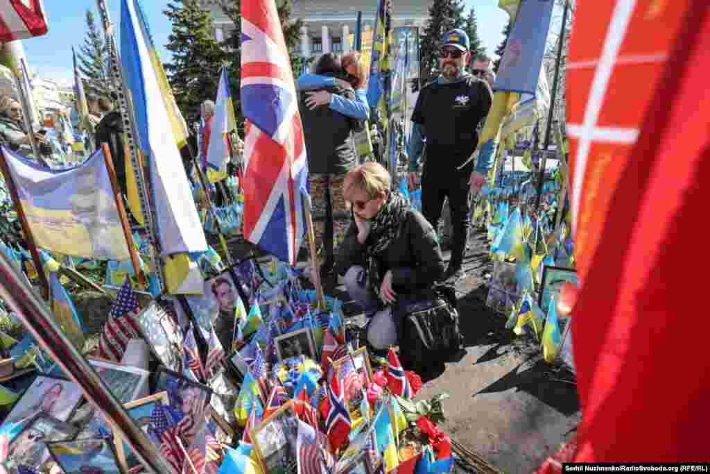 Люди у портретов павших добровольцев во время акции памяти 14 марта.По сообщениям, с начала полномасштабного вторжения России в Украине погибло по меньшей мере 50 американцев, большинство из них — ветераны 