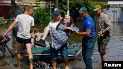 A member of Russia's Emergencies Ministry and a local resident carry an elderly woman during the evacuation of residents from a flooded area in the town of Hola Prystan in the Kherson region of Russian-controlled Ukraine on June 8.